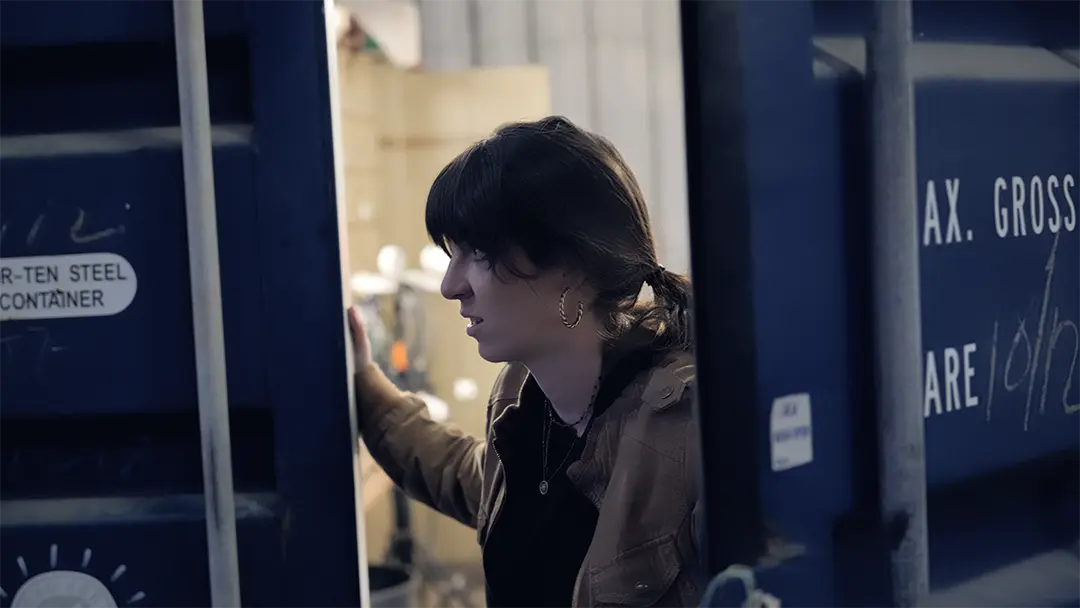 L'actrice observe un container bleu dans une prise du film